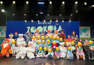 Pamiątkowe zdjęcie przedszkolaków z aktorami w kostiumach zwierząt na scenie po musicalu „ZOOkoła świata"