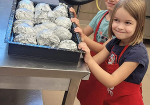 Dzieci, które z wielkim zapałem przygotowują pieczone ziemniaki.