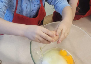 Dzieci wbijają jajko do miski z mąką
