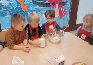 Dzieci dosypują mąkę do miski