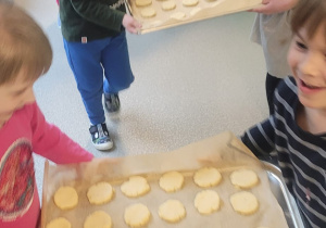 Dzieci idące do kuchni przedszkolnej z blachami ciastek do wypieczenia