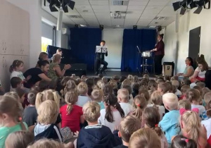Dzieci siedzące na sali słuchając koncertu.