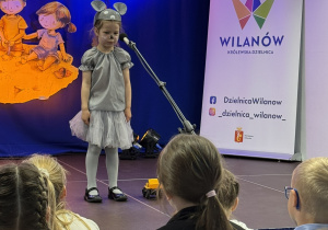 Dziewczynka przebrana za myszkę, recytująca wiersz na scenie podczas IV Warszawskiego Konkursu Recytatorskiego w Dzielnicy Wilanów.