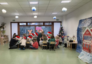 Świąteczne warsztaty w sali przedszkolnej, podczas których dzieci wspólnie z rodzicami tworzą ozdoby.