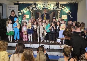 Uroczysty finał Warszawskiego Konkursu Recytatorskiego, podczas którego dzieci prezentują się na scenie, odbierają dyplomy i wspólnie świętują udział w wydarzeniu.