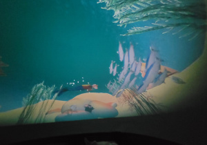 Dzieci uczestniczą w seansie Kina Sferycznego, oglądając edukacyjne filmy 3D o zwierzętach i podwodnym świecie wewnątrz mobilnej kopuły projekcyjnej.
